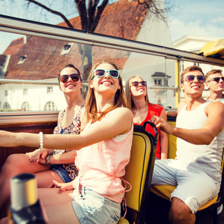 Adults in sunglasses on a  open tour bus.