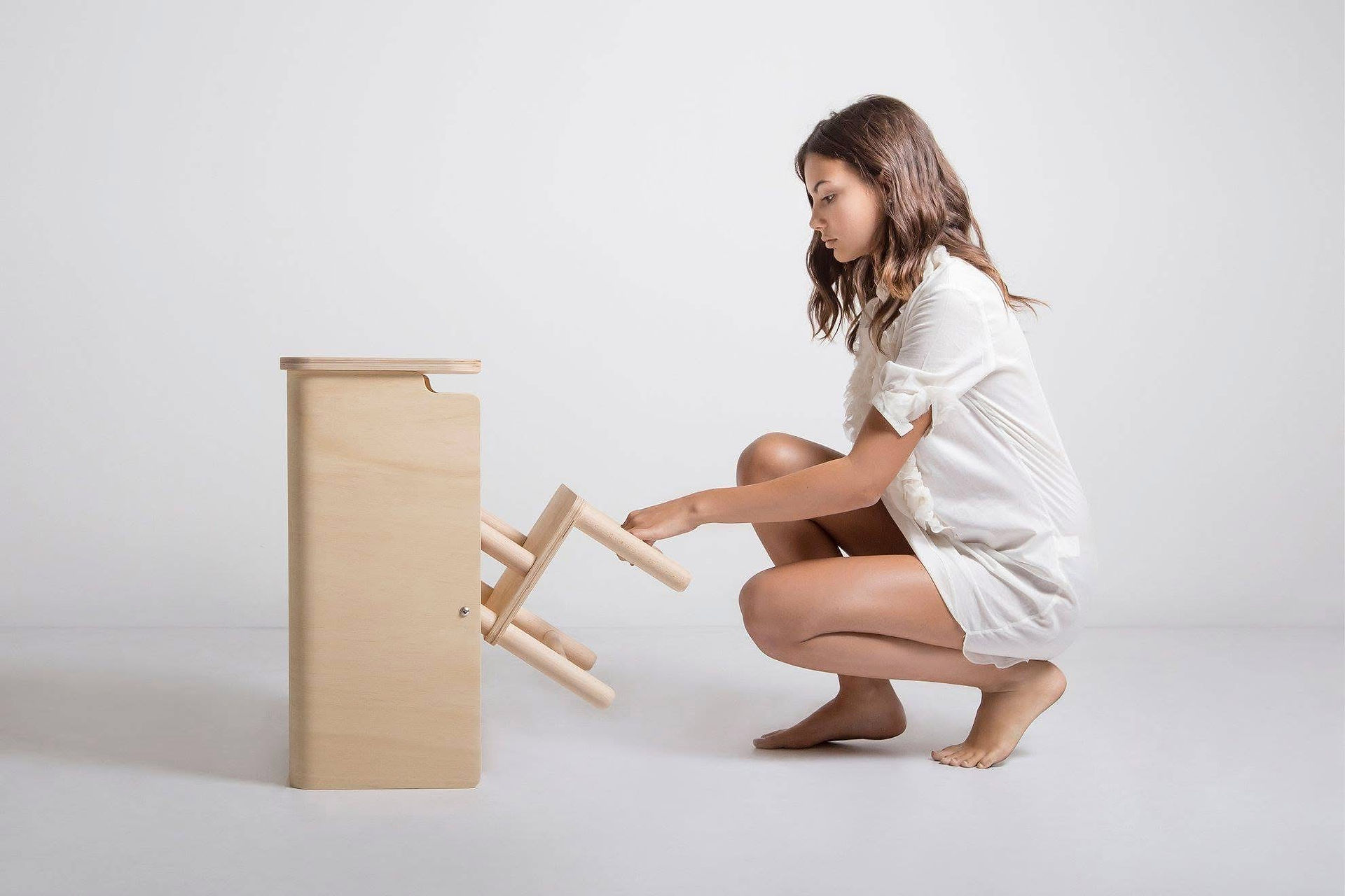 Donna estrae scaletta da mobile in legno