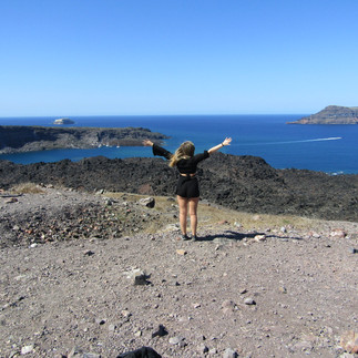 A person with their hands up on top of a volcano