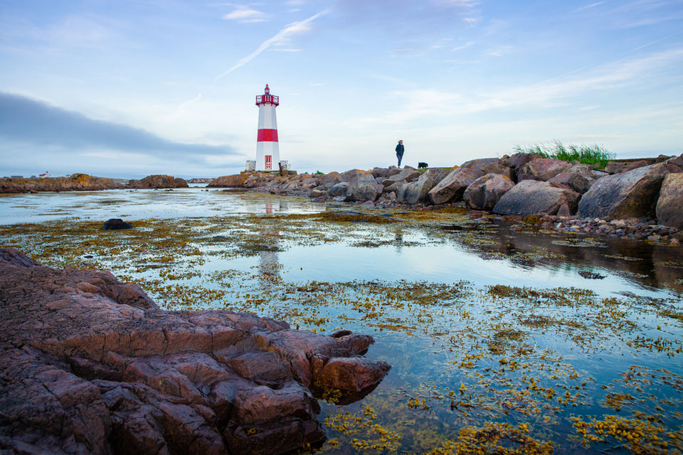 Pointe aux Canons Lighthouse in Saint Pierre and Miquelon, surrounded by the Atlantic Ocean, with a scenic trail leading to the site, ideal for a scenic stroll.