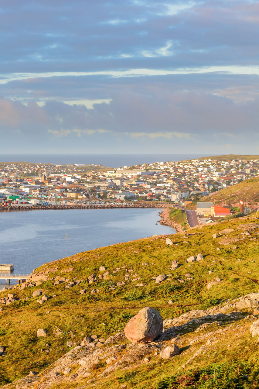 Vue du centre-ville de Saint-Pierre-et-Miquelon depuis un cadre naturel, offrant un contraste entre la nature préservée et l’architecture colorée de la ville.