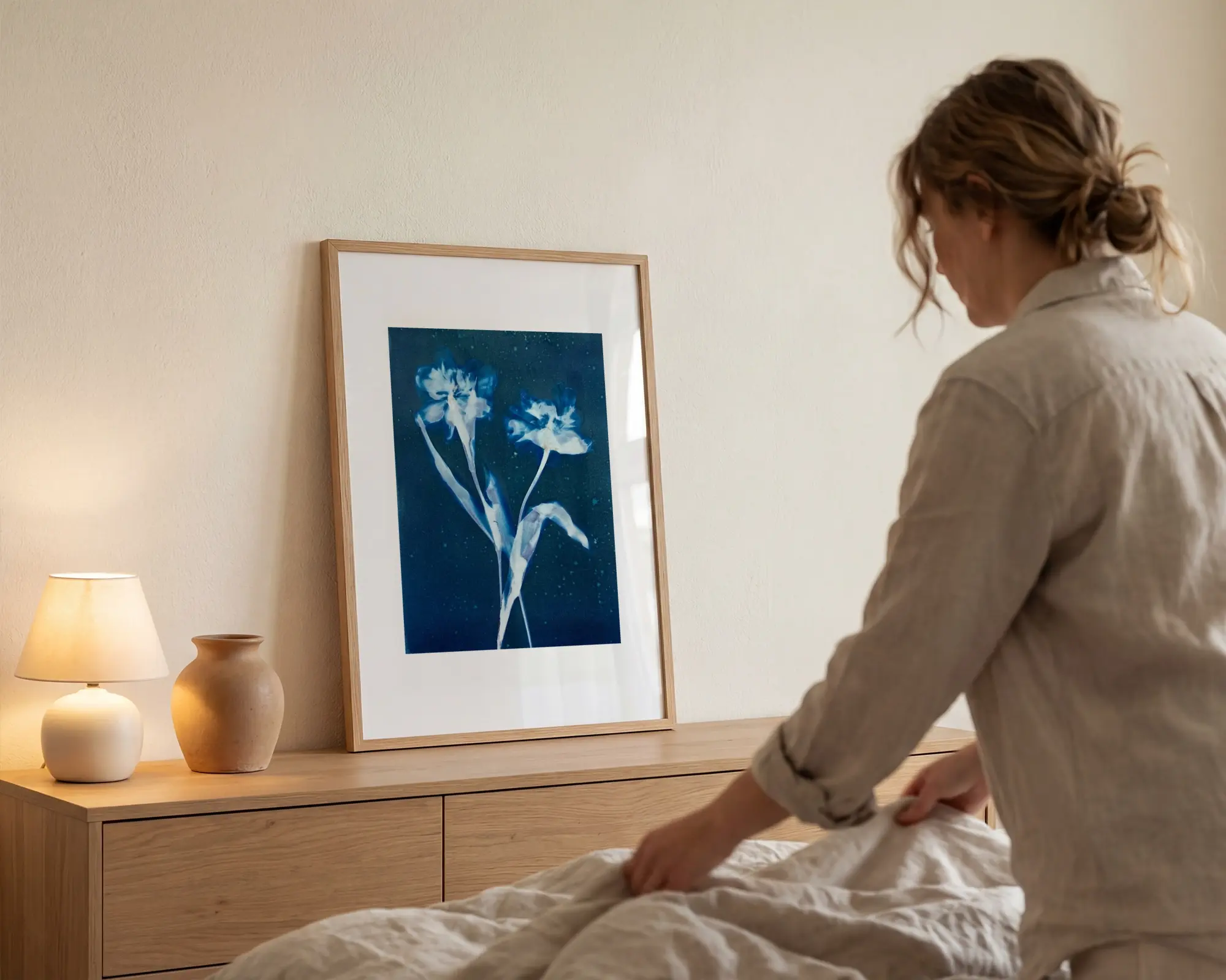 Inramad botanisk konst med tulpaner på väggen i ett sovrum med naturmaterial.