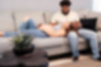 Pregnant woman lying on the couch with her head on her husband's lap