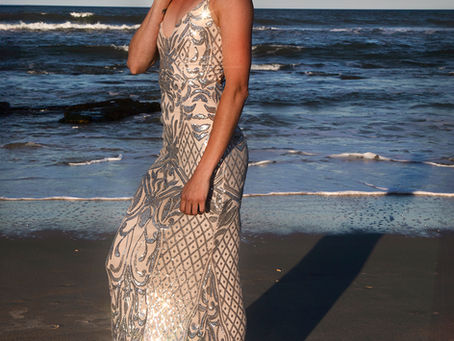 Woman in a golden dress on the beach at sunset