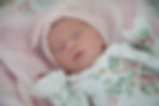 A newborn baby girl lying a pink blanket