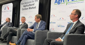 four men in suits sitting in chairs in front of marketing banners