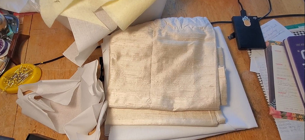 A selection of ivory and white fabrics on a table.