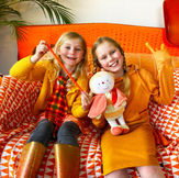 2 children dressed in orange sat on an orange sofa