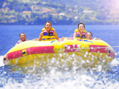 Tourists enjoying an exciting banana boat ride in Nusa Dua, a popular water sport activity before dining at Acala Bar & Bistro