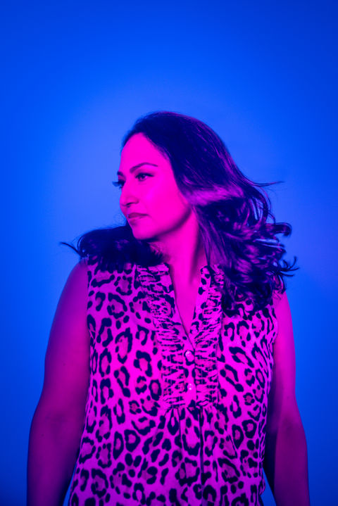 A woman poses for a unique and artistic studio portrait with blue and pink lighting
