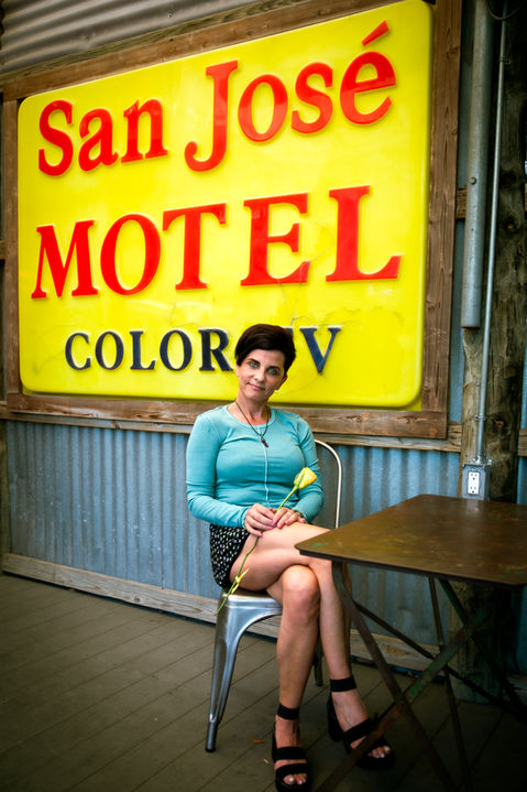 A woman poses for a dating portrait in front of a vintage sign in Austin, TX