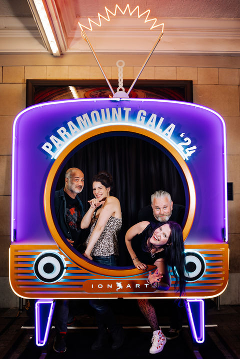 People pose in a neon TV photo booth at the Paramount Gala