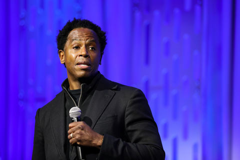 A speaker on a large stage during an education conference