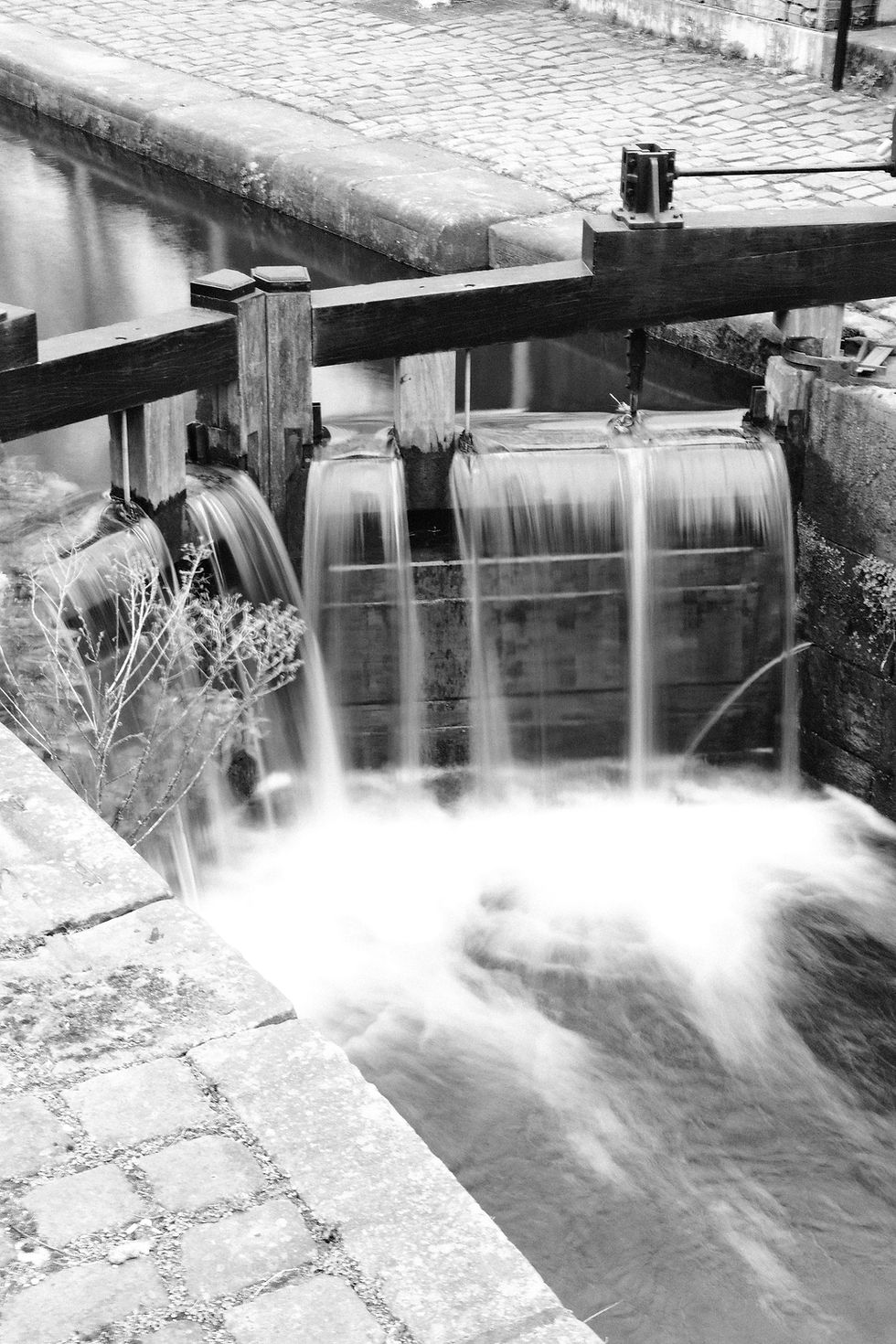 A black and white photograph of the lock on the Rochdale Canal in Ancoats, Manchester, taken with a slow shutter speed.
