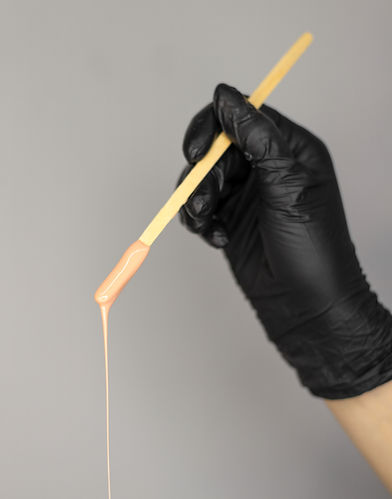 Gloved hand with waxing stick and dripping wax