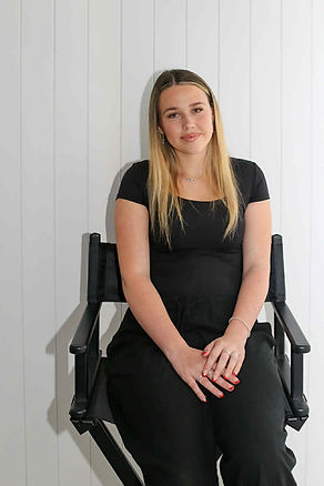 lacey with blonde hair sitting on a black director's chair.