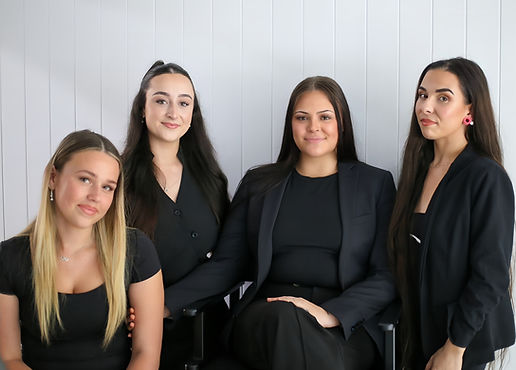 Four women smiling, dressed in black.