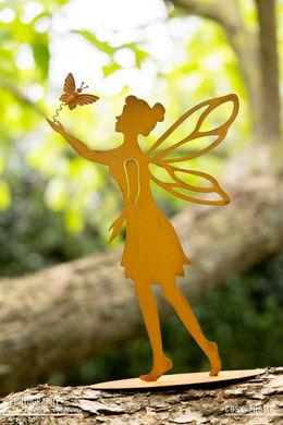 Sfeerfoto van een metalen roesten beeldje van een elfje op een boomtak.