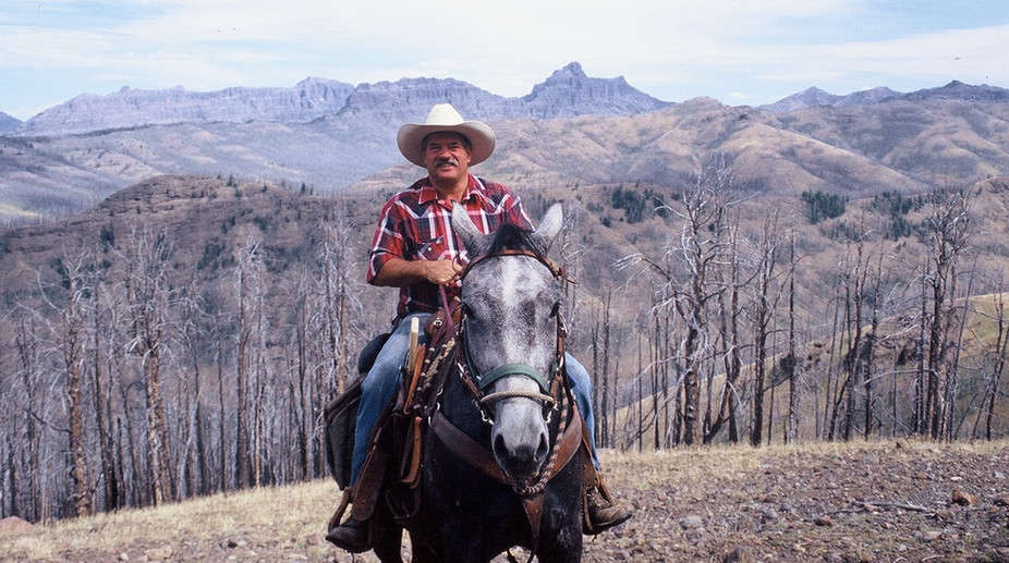 Victor Jackson, in cowboy clothes on gray horse, pictures on mountain during Hoodoo Pack Trip in 2001