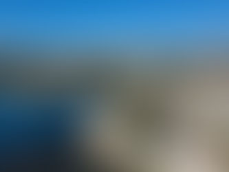 Vue aérienne d’une baie méditerranéenne, promenade bordée de palmiers, immeubles côtiers et mer bleu vif sous ciel clair, Antibes Ponteil.