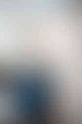 A sitting area with blue chairs and yellow pops of color on the cushions. A warm beige and cream wainscoting adorn the walls.