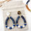 Miniature : Boucles d'oreilles avec arcs en résine bleue et perles bleues et blanches, accrochées à des attaches dorées texturées.