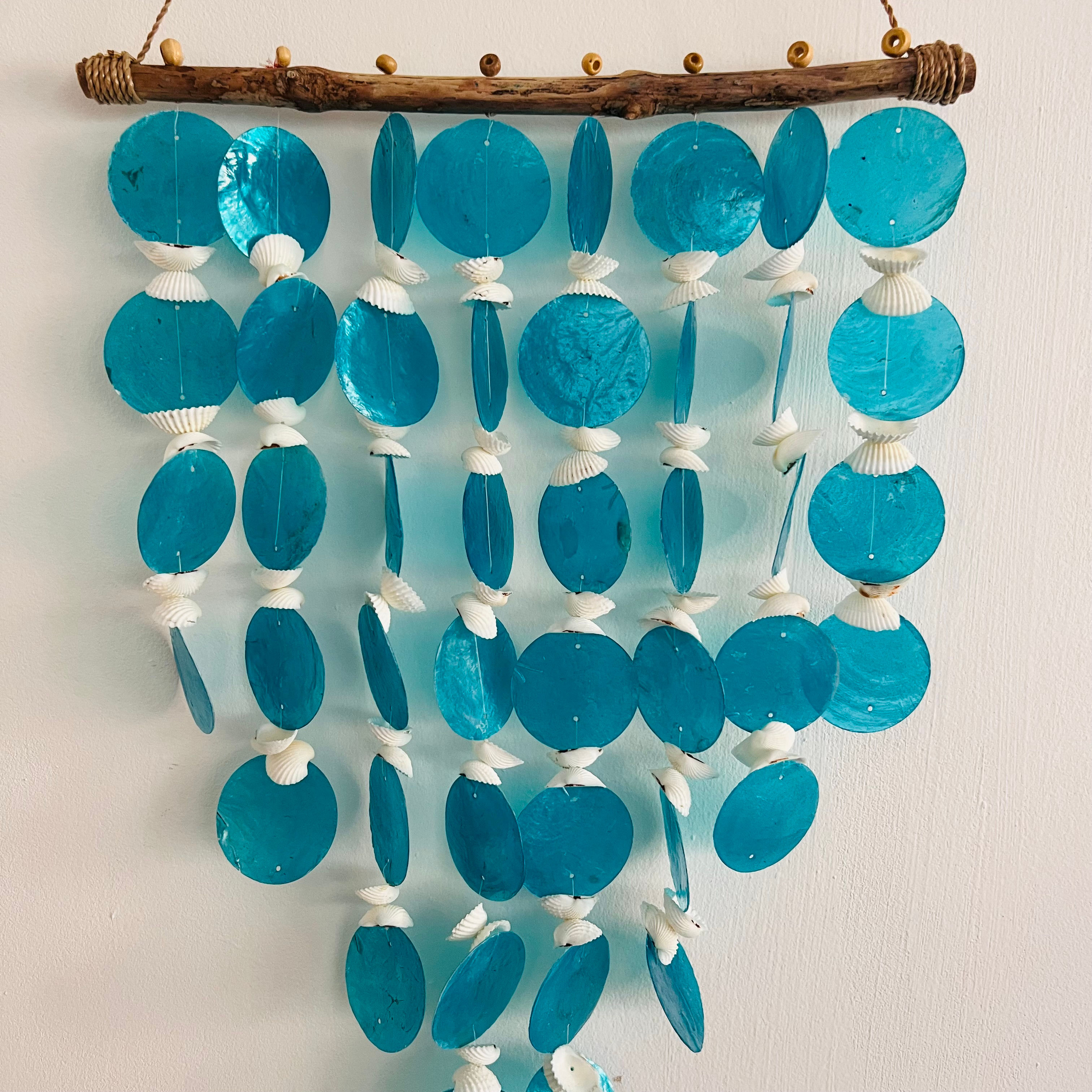 Suspension décorative en bois flotté avec disques bleus et coquillages blancs, idéale pour une décoration murale bohème et na