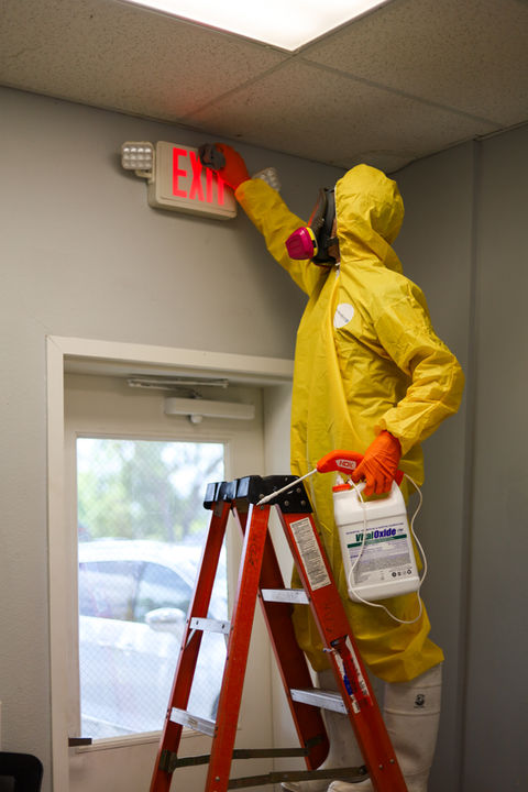 Coast 2 Coast Restorations technician in a hazmat suit holding Vital Oxide while cleaning and sanitizing a Central Florida property