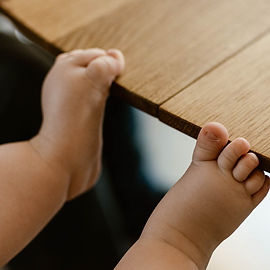 Babyfüße krallen sich beim Babyshooting am Tisch fest
