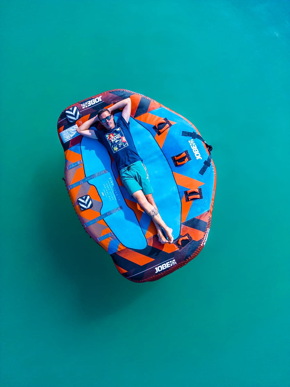 Homme allongé sur une bouée flottant dans l'eau turquoise.