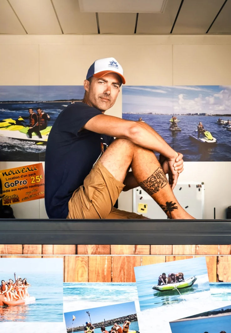 Homme assis devant des photos de sports nautiques.