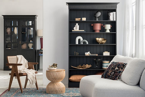 Home staged for sale cream couch, rattan side table, black bookcare with neatly styled items