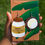 Thumbnail: Handmade statement earrings of a coconut oil jar and a coconut fruit with a brown and green palm tree earring holder