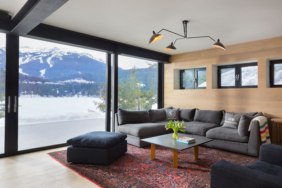 Cost to build a home vancouver. Custom home renovations. Modern living room with gray sectional, ottoman and rug, overlooking snowy mountains; pillows read Keep Tips Up and Experts Only.