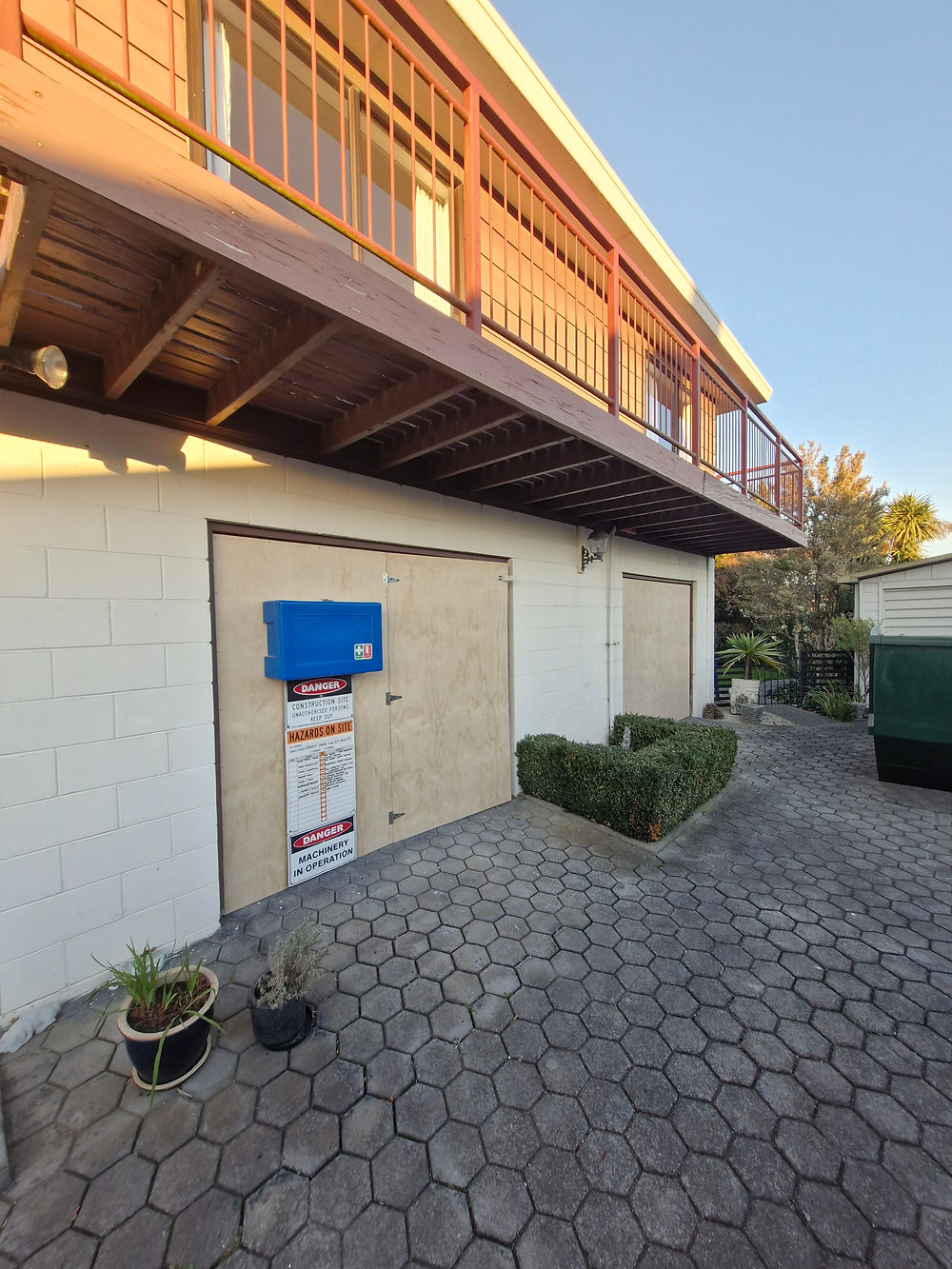 Two-story white building under renovation with plywood door