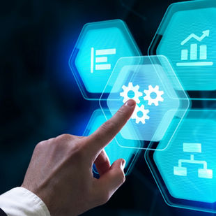 A hand in a suit taps a glowing blue digital gear icon on a virtual screen with graphs and flowcharts, evoking innovation and technology.
