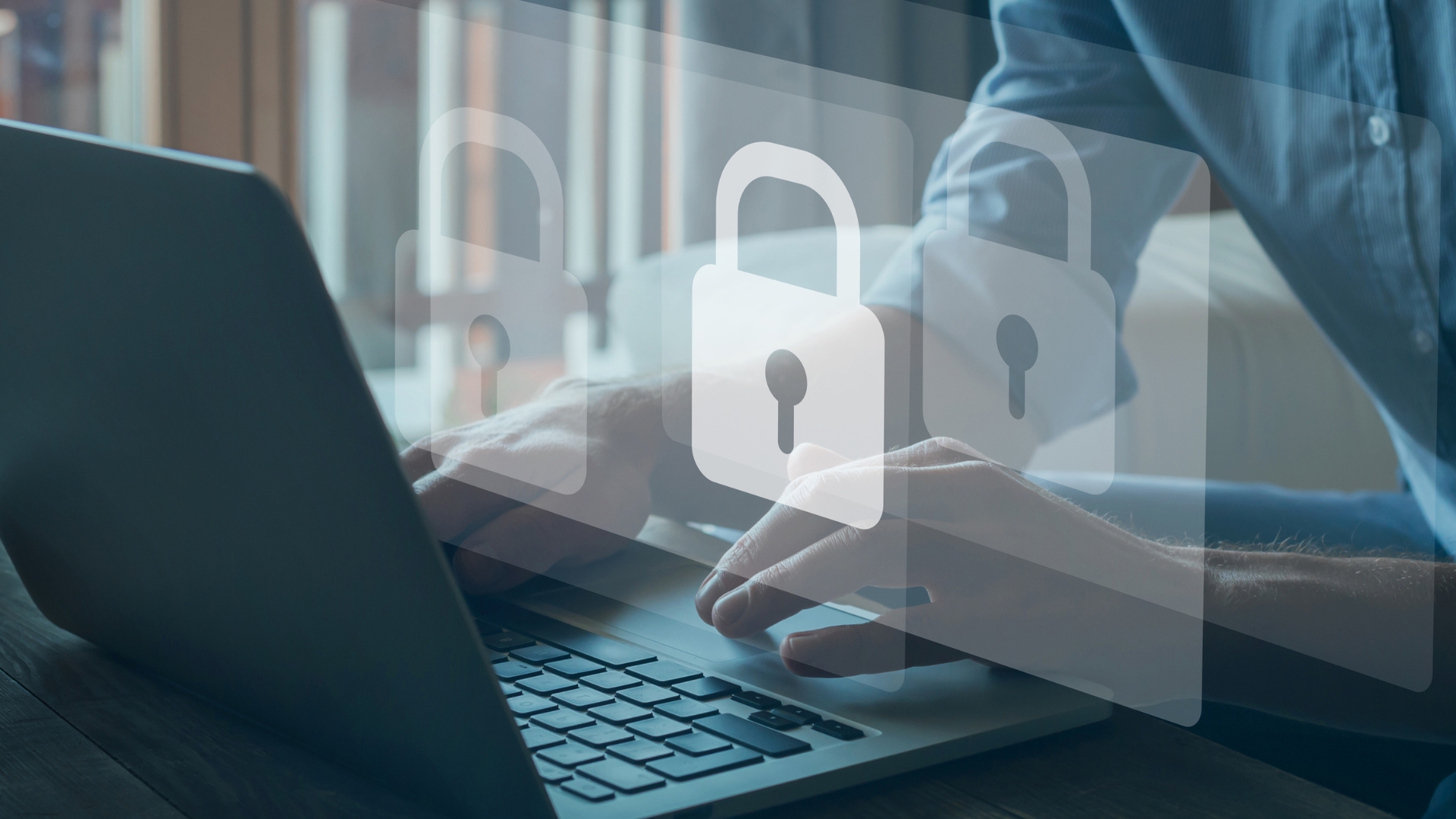 Hands typing on a laptop with overlayed padlock icons, symbolizing cybersecurity. Blurred background with natural light from windows.