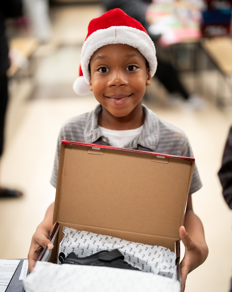 Happy young boy wearing a Santa hat showing his new shoes