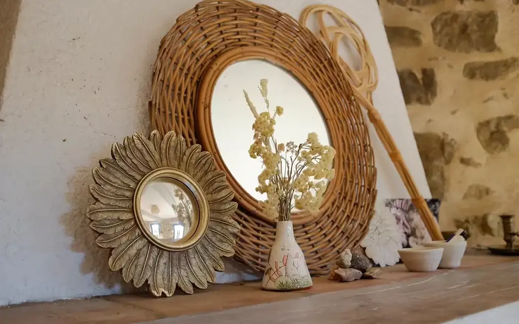 Mirroirs en rotin et métal posés sur une cheminée avec un bouquet de fleur séché jaune
