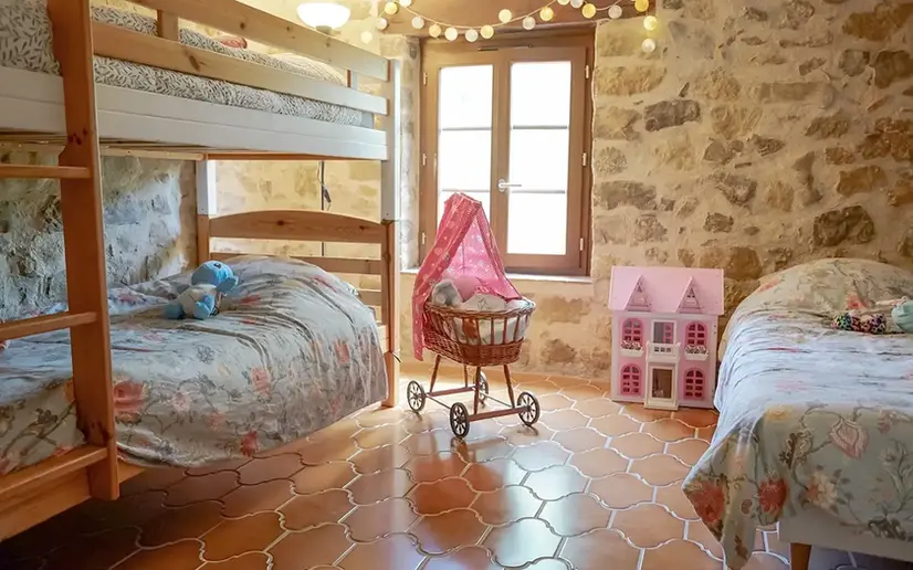Lit superposé d'une chambre d'enfant avec maison de poupée et landeau en jouet.