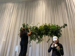 Florist making green square arbour head table backdrop