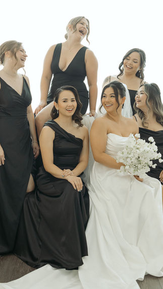 Smiling Bride in white and Bridesmaids in Black dresses with all white floral bouquets