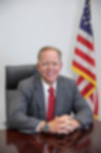 Herb Morgan is sitting at his desk with an American Flag behind him.
