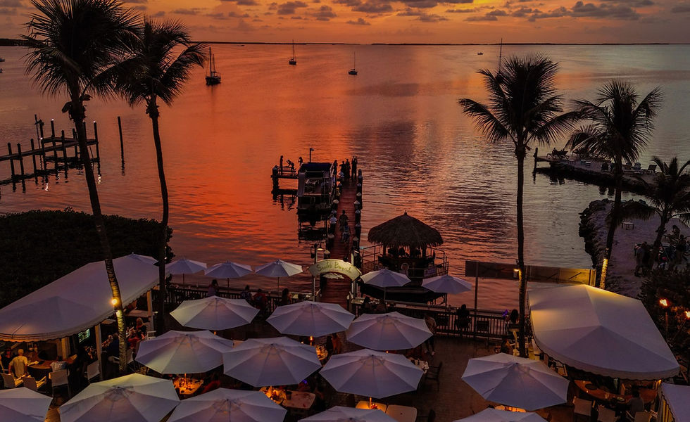 Eye-level view of a family sitting at an outdoor bayside table with live music nearby.