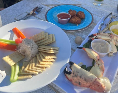Close-up view of stone crab claws with key lime mustard sauce on an outdoor table.