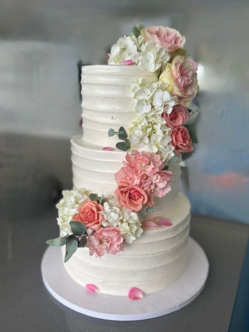 Three-tier white textured cake with pink and white flowers