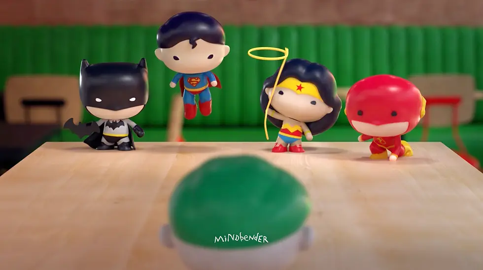 Cute toy superheroes, including Batman and Superman, on a table with green and brown background. "Mindbender" text visible.