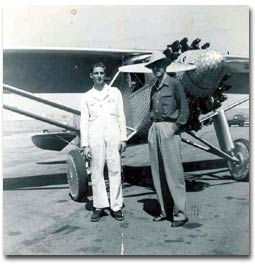 Image of two men standing in front of a replica of the Spirit of Saint Louis Plane