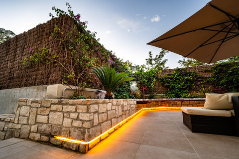 Disseny i construcció de gran jardinera feta a mida en una terrassa enrajolada. Tanca de bruc, plantes mediterranies, reg de degoteig i il·luminació LED.