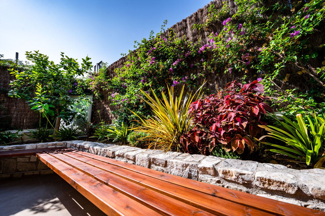 Jardinera d'obra amb pedra natural i banc de fusta integrat.